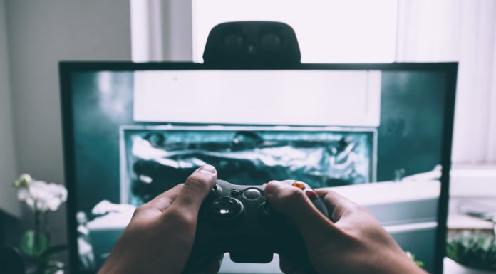 Deux mains tenant une manette de jeu devant un écran pour quelle console choisir