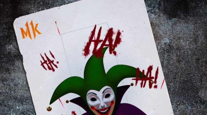 La carte du joker pour Mortal Kombat 11 avec la tête du clown au centre, les lettres HA HA HA écrites un peu partout et le logo MK de chaque côté