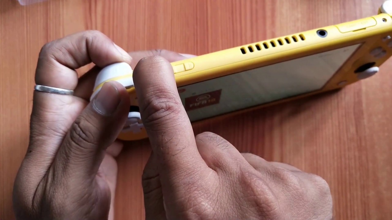 Un pouce pressant le bouton d'alimentation de la Nintendo Switch