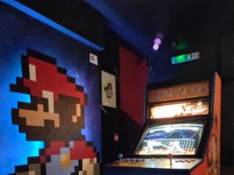 Borne d'arcade Street Fighter avec mario peint sur le mur d'à côté