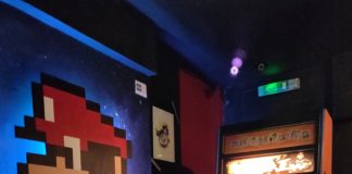 Borne d'arcade Street Fighter avec mario peint sur le mur d'à côté