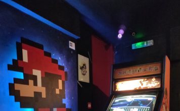 Borne d'arcade Street Fighter avec mario peint sur le mur d'à côté