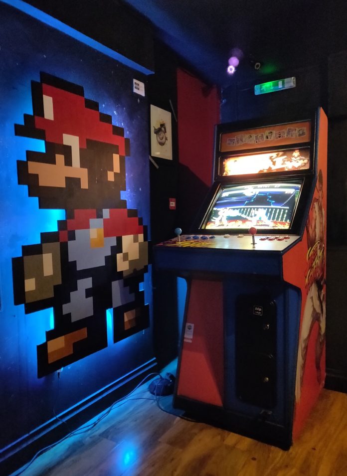 Borne d'arcade Street Fighter avec mario peint sur le mur d'à côté