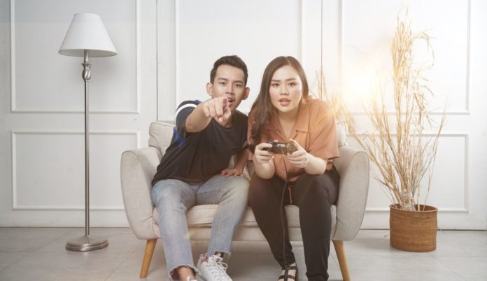Un couple qui joue aux jeux vidéo assis sur une chaise